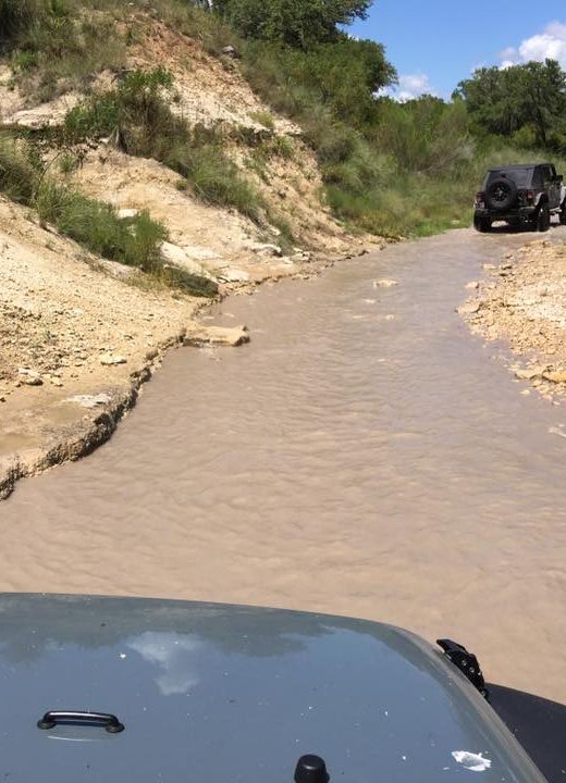 Jeep going up a creek towards waterfalls