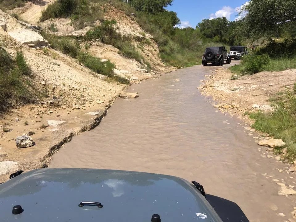 Jeep going up a creek towards waterfalls 